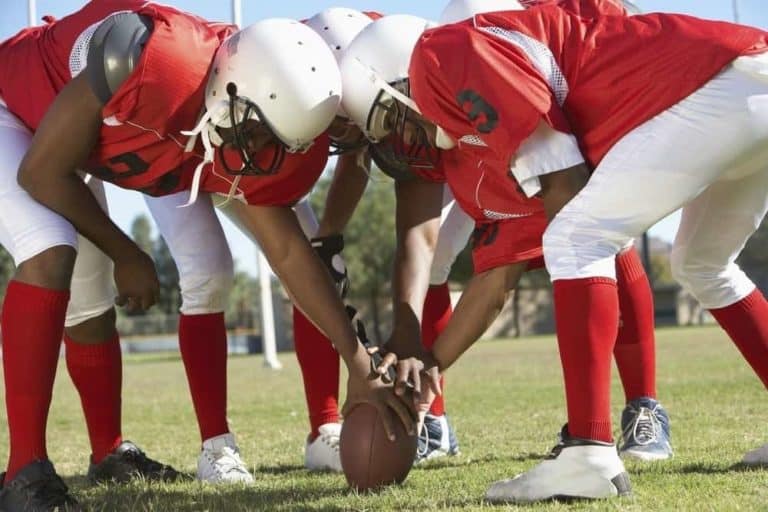 Football players in a huddle around the ball