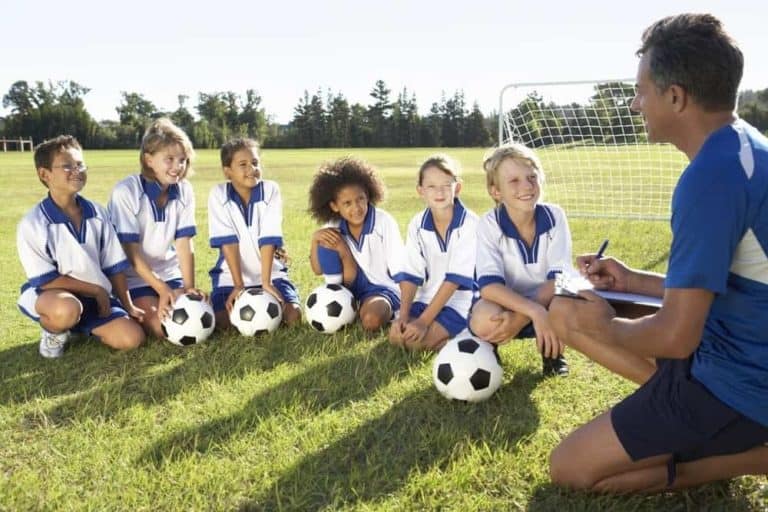 A coach talking to a soccer team made up of young kids.