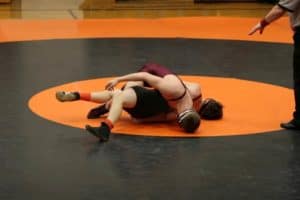 Wrestlers on a mat in the middle of a match.