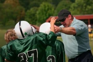 A coach encouraging a youth football team before a game.