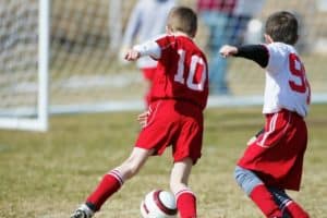 Two boys fighting for the ball during a soccer match.