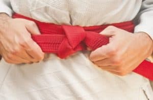 A red belt being pulled tight on a Brazilian Jiu-jitsu gi.