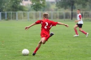 A boy kicking a soccer ball.