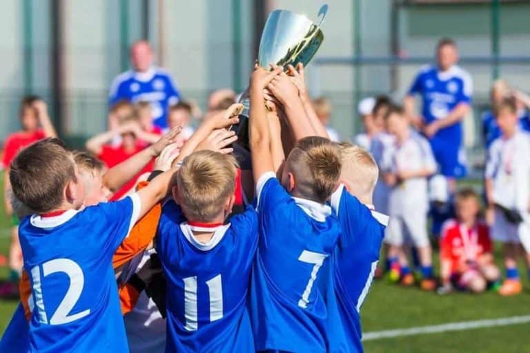 A youth soccer team holding their trophy in the air.
