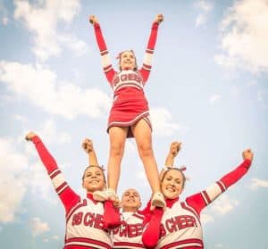 Cheerleaders lifting another girl in their squad.