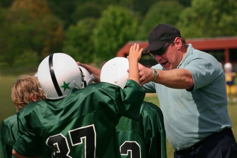 A coach encouraging young football players.