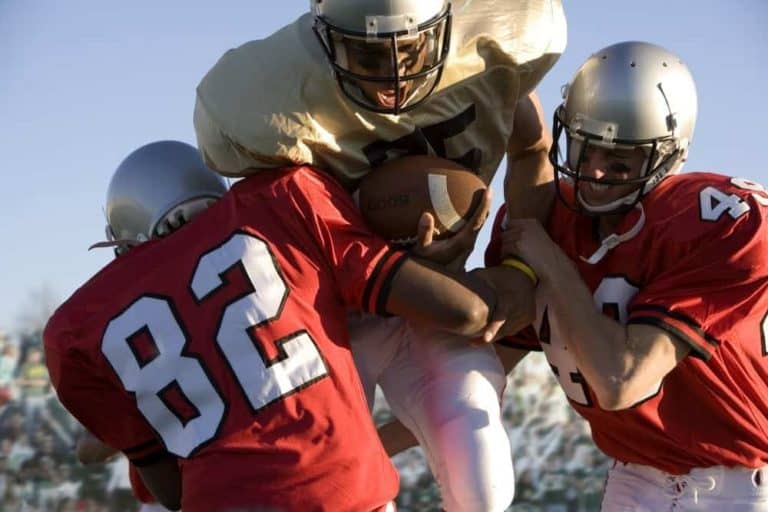 Defenders tackling a running back during a football game.