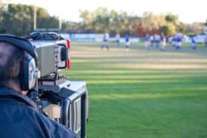 A man filming a soccer game.