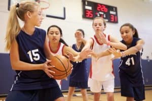 Middle school age girls playing basketball.