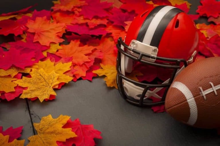 A helmet, football, and fall leaves.