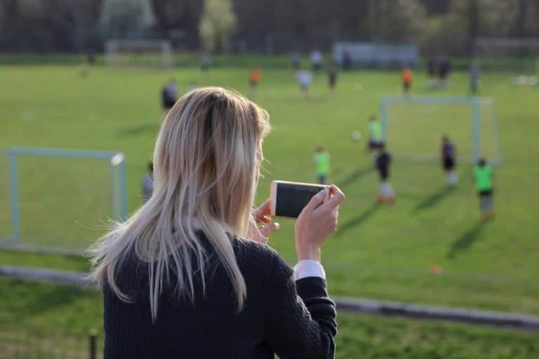 A mother taking photos at her son's soccer game.