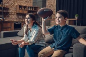 A boy watching a football game with his mother.