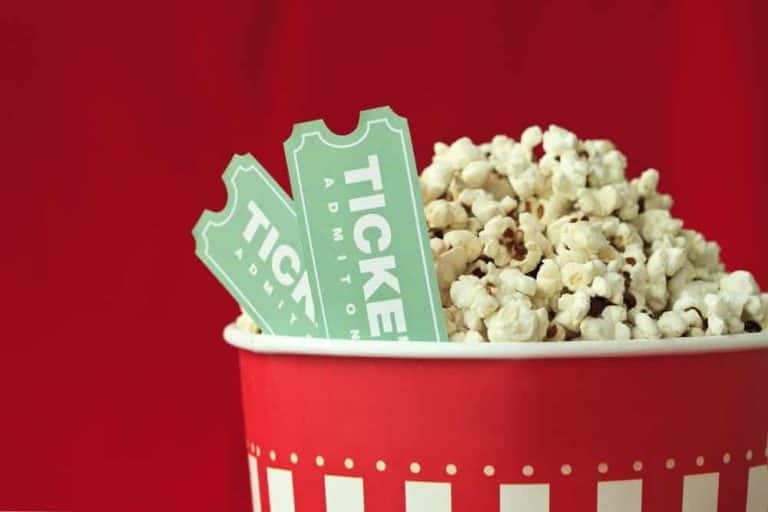 A bucket of popcorn with two movie tickets.