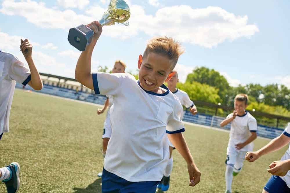 boy holding trophy on soccer field