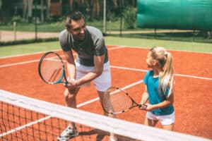 father and daughter play tennis