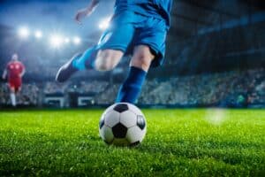 Football World Championship: Soccer Player Runs to Kick the Ball. Ball on the Grass Field of Arena, Full Stadium of Crowd Cheers. International Tournament. Cinematic Shot Captures Victory.