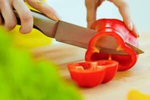 woman cutting red bell pepper